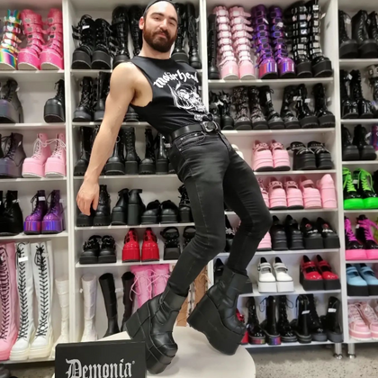 Matthew Pope modelling a pair of STACK-201 Demonia Black Ankle Boots with Platform. Wearing Motorhead Singlet, Black Jeans and a black belt.