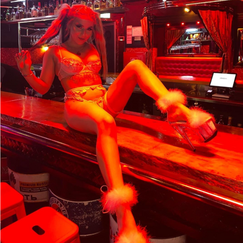 Exotic Dancer in pigtails and pink lingerie sitting on a bar table wearing fluffy pink platform heels ADORE-724F